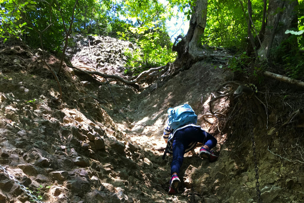 ガレ場の鎖場を登る男性登山者