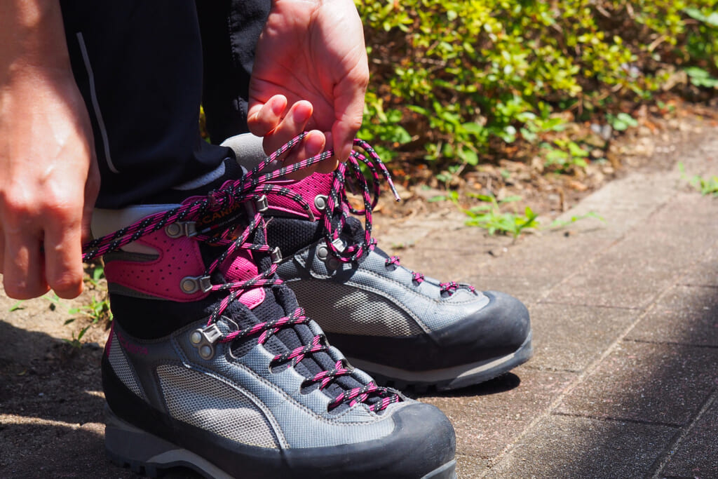 登山靴の靴紐を結ぶ女性