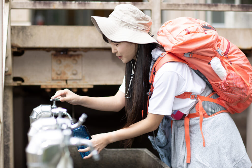 山小屋でボトルに水を補給する女性ハイカー