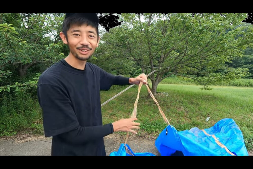 ブルーシートでテントを立てるやまださん